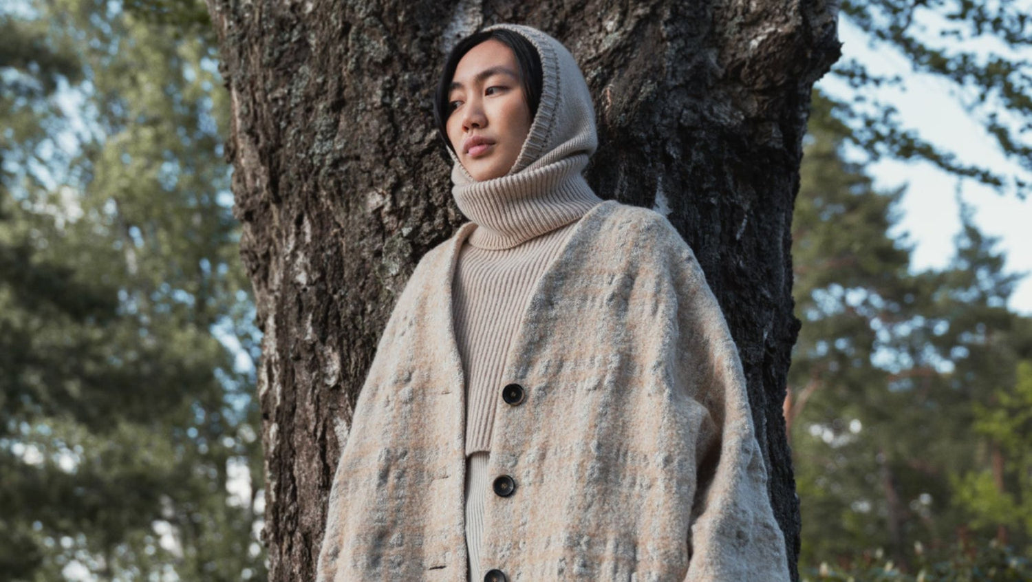 A woman standing by a tree, wearing Samuji balaclava