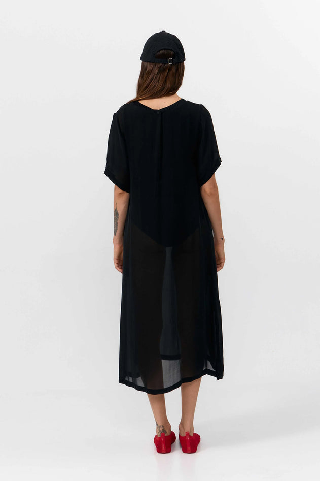 Person wearing a black dress and red shoes on a white background