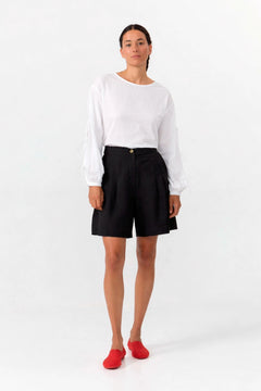 Person wearing a white shirt and black shorts on a white background