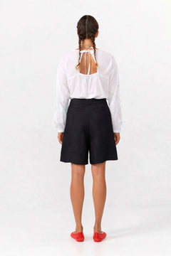 Person wearing a white blouse and black shorts on a white background