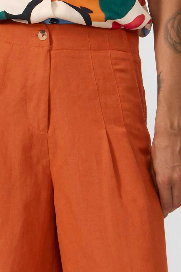 Close-up of orange pants with a colorful shirt and tattooed arm in the background