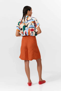 Woman wearing a colorful shirt and orange skirt on a white background