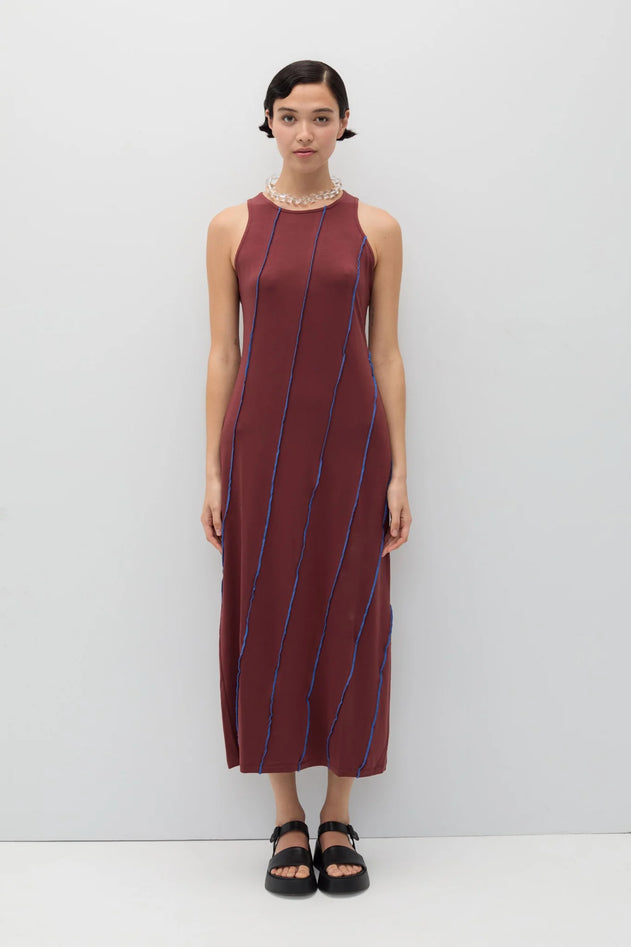 Woman wearing a maroon dress with blue stripes against a white background