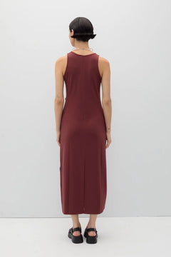 Person wearing a burgundy sleeveless dress against a white background