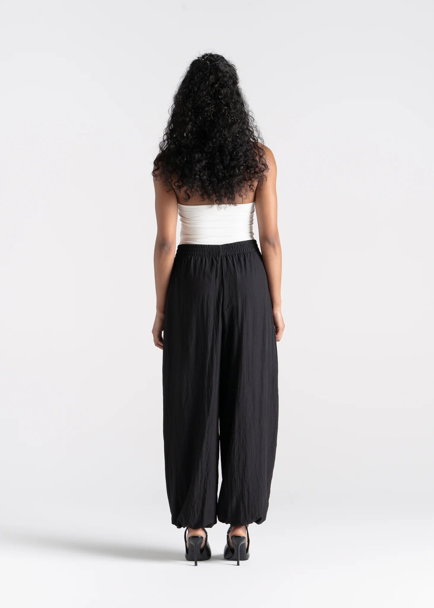 Woman wearing a white top and black high-waisted pants on a white background