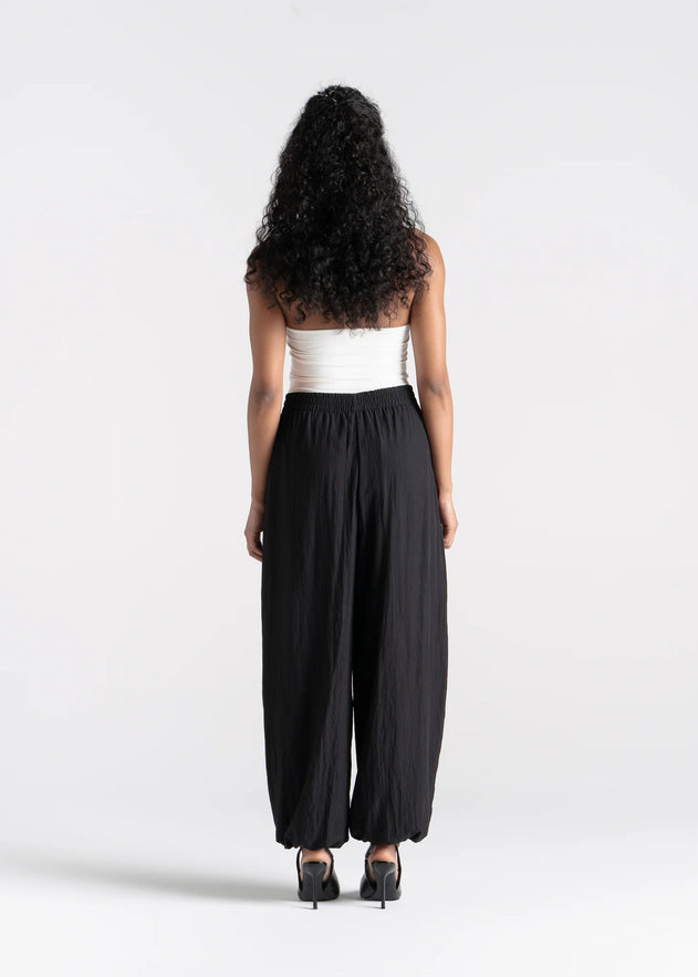 Woman wearing a white top and black high-waisted pants on a white background