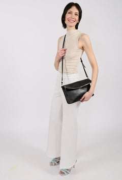 Woman holding a black handbag against a white background
