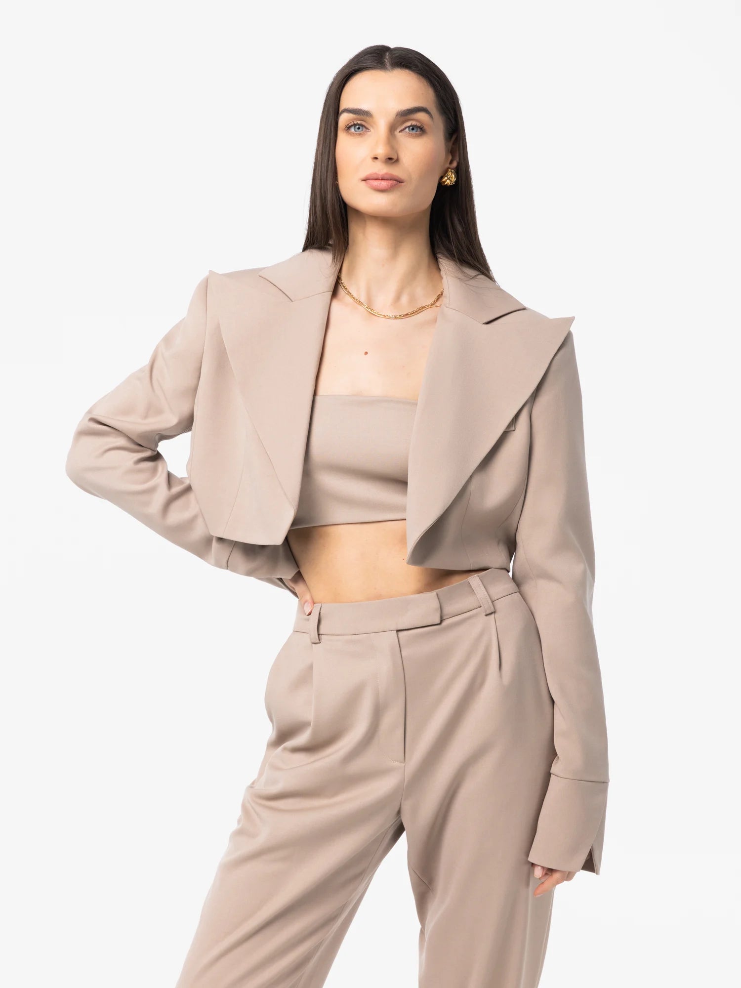 Woman wearing a beige blazer and pants on a white background