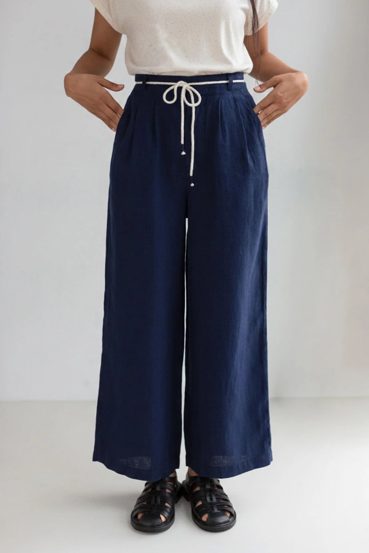 Person wearing navy wide-leg pants with a white top on a plain background