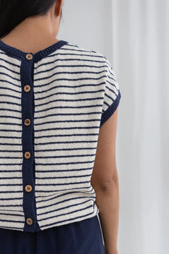 Navy and white striped shirt with button details on a plain background