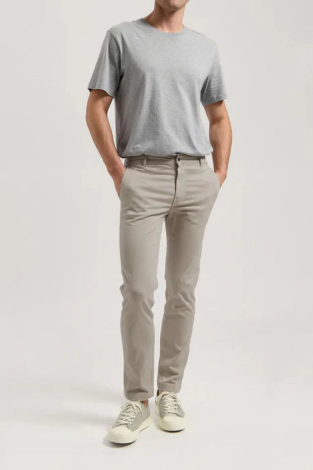 Person wearing a gray t-shirt and beige pants on a white background