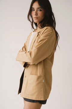 Woman wearing a beige jacket against a plain background