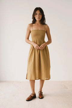 Woman wearing a mustard yellow dress against a white background