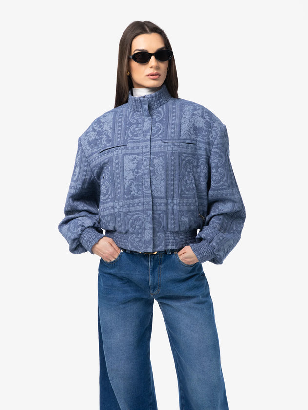 Woman wearing a blue patterned shirt and jeans on a white background