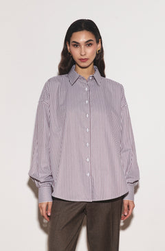 Woman wearing a striped shirt and brown pants on a white background