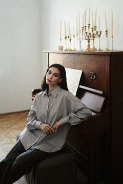 Woman sitting on a piano with candles in the background