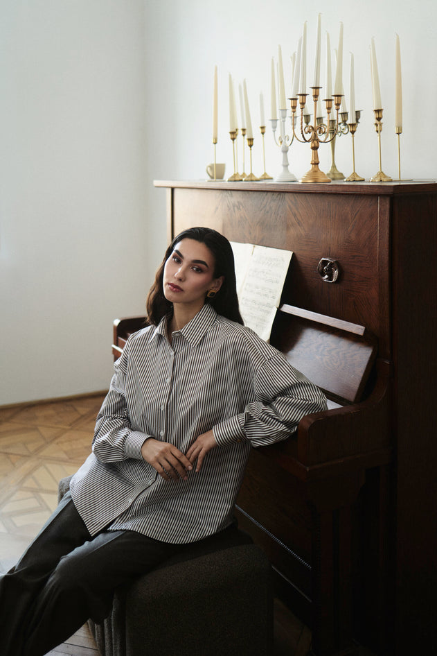 Woman sitting on a piano with candles in the background