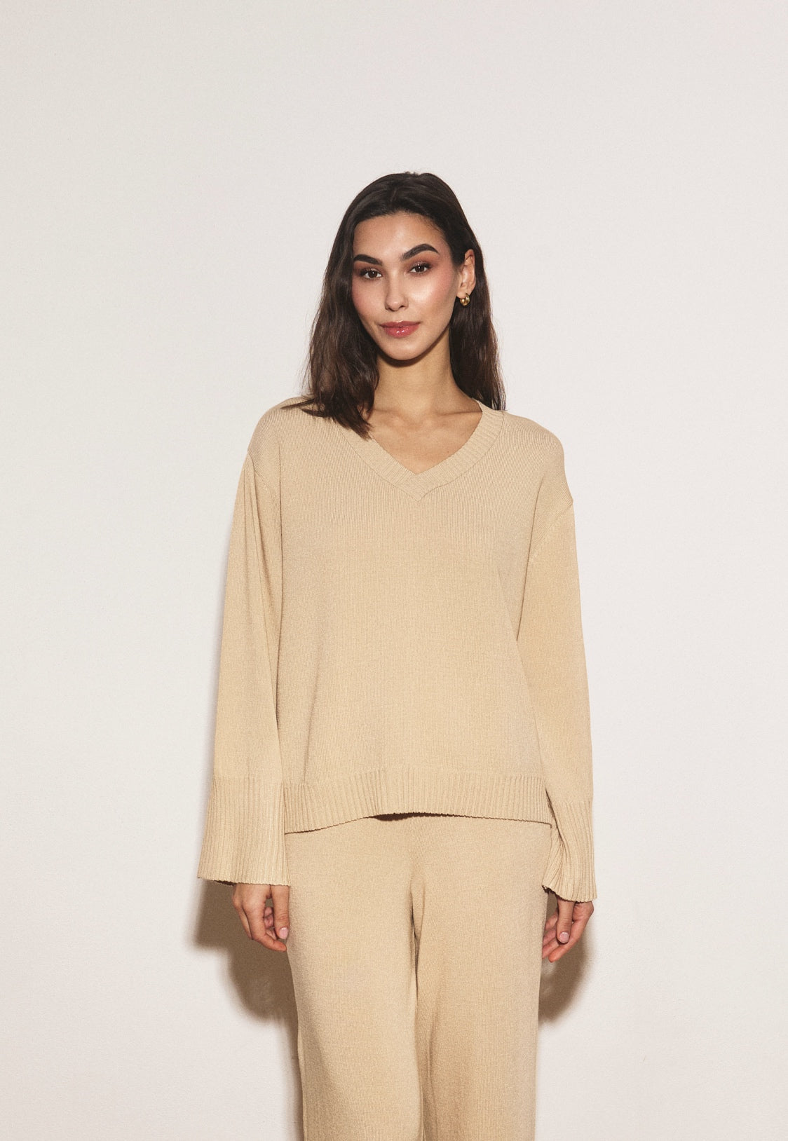 Woman wearing a beige outfit against a white background