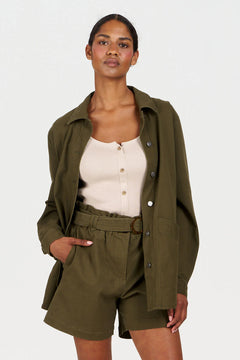 Woman wearing an olive green jacket and shorts set on a white background