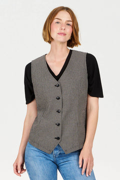 Woman wearing a patterned vest over a black shirt with a plain background