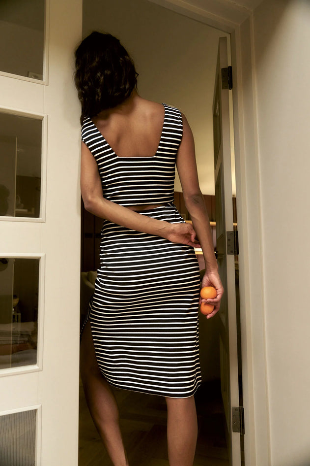 Person wearing a black and white striped dress standing in a doorway.