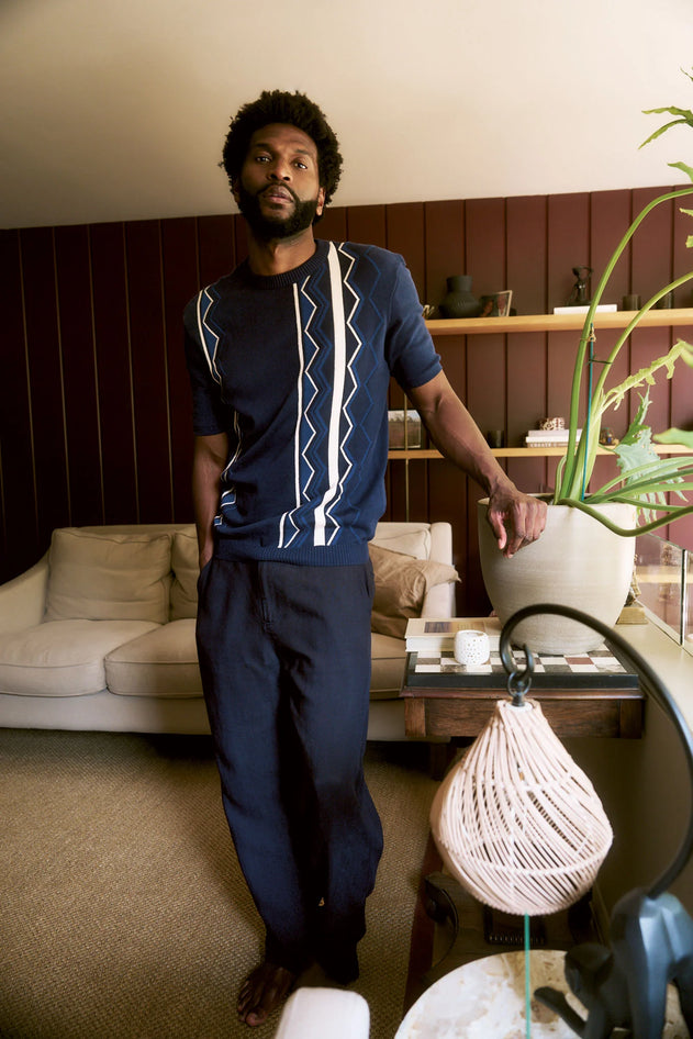 Man standing in a living room with a couch and decorative items.