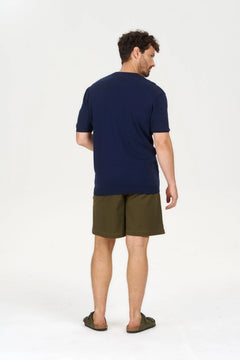 Man wearing a navy t-shirt and green shorts on a white background