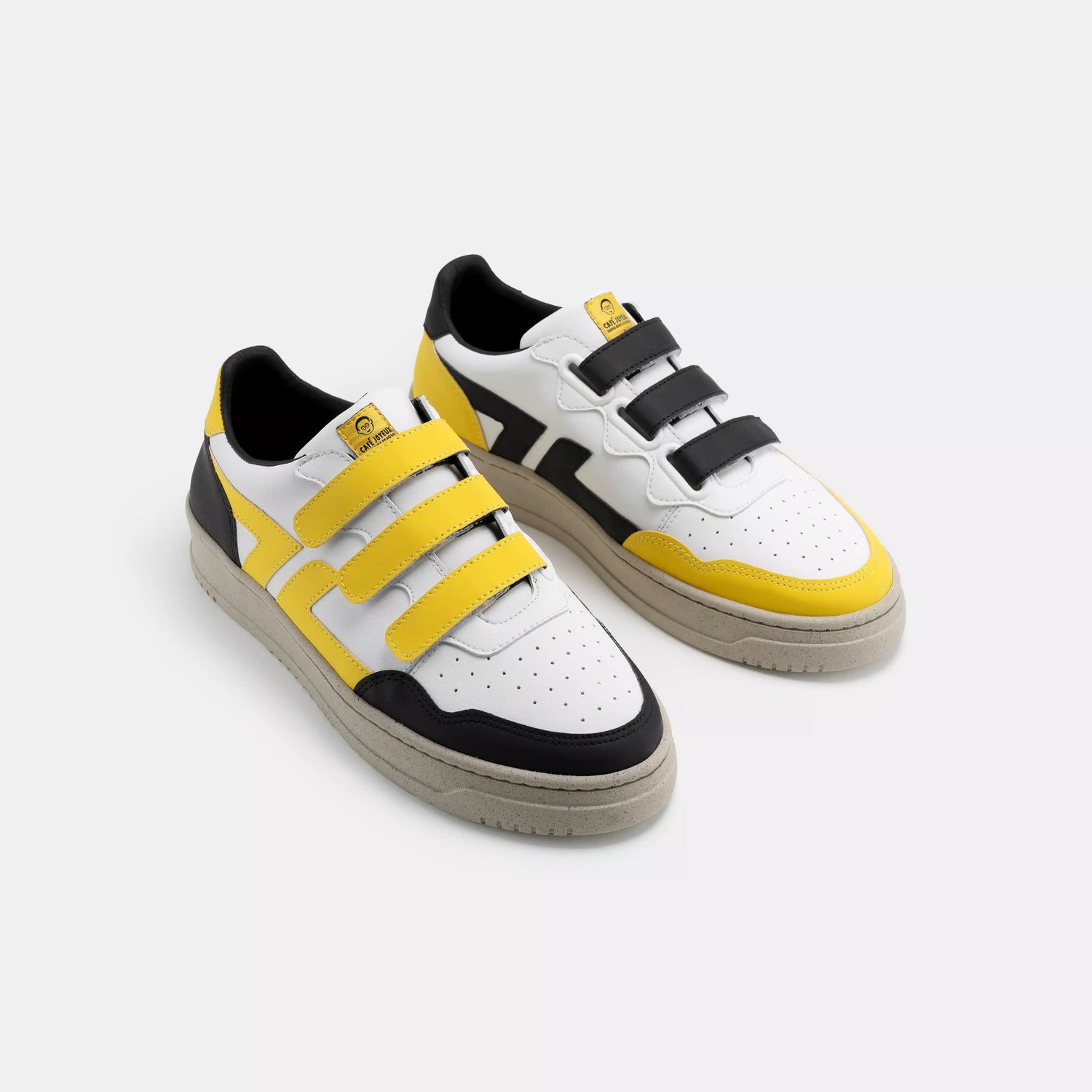 White sneakers with yellow and black accents on a light gray background