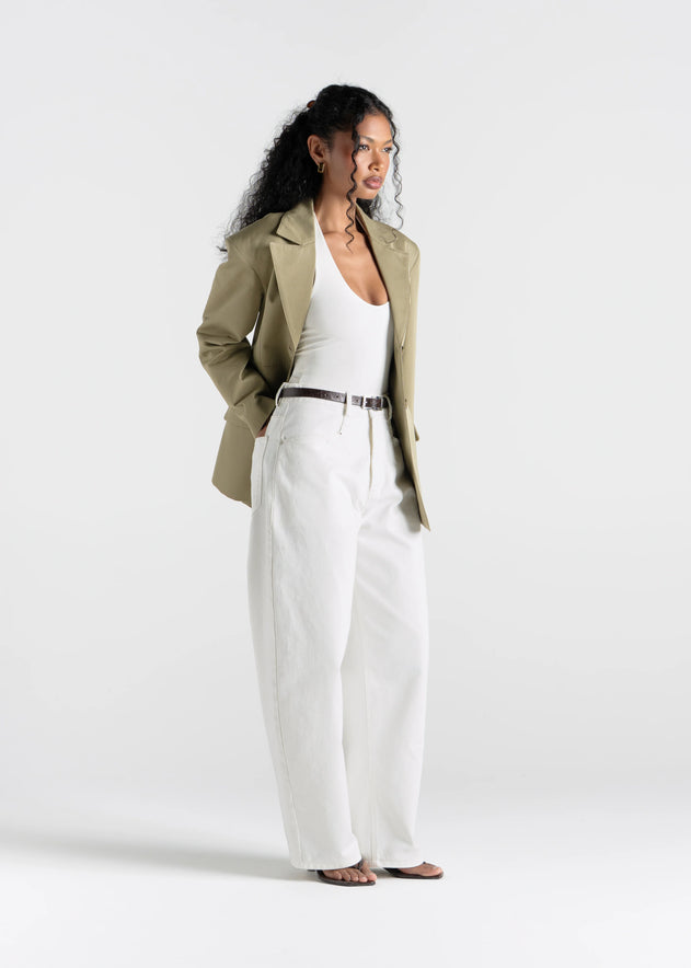 Woman wearing a green jacket and white pants on a white background