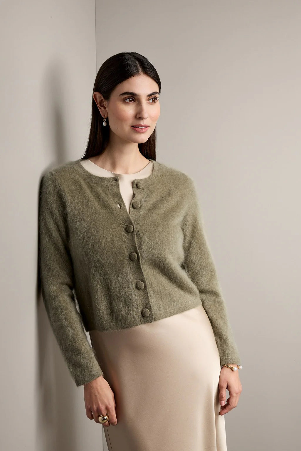 Woman wearing a green cardigan against a plain background