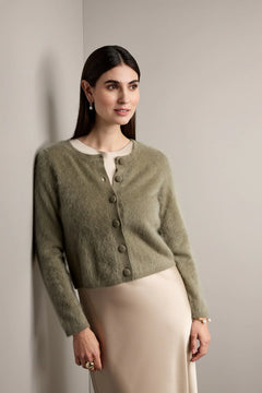 Woman wearing a green cardigan against a plain background