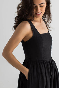 Woman wearing a black sleeveless dress against a plain background