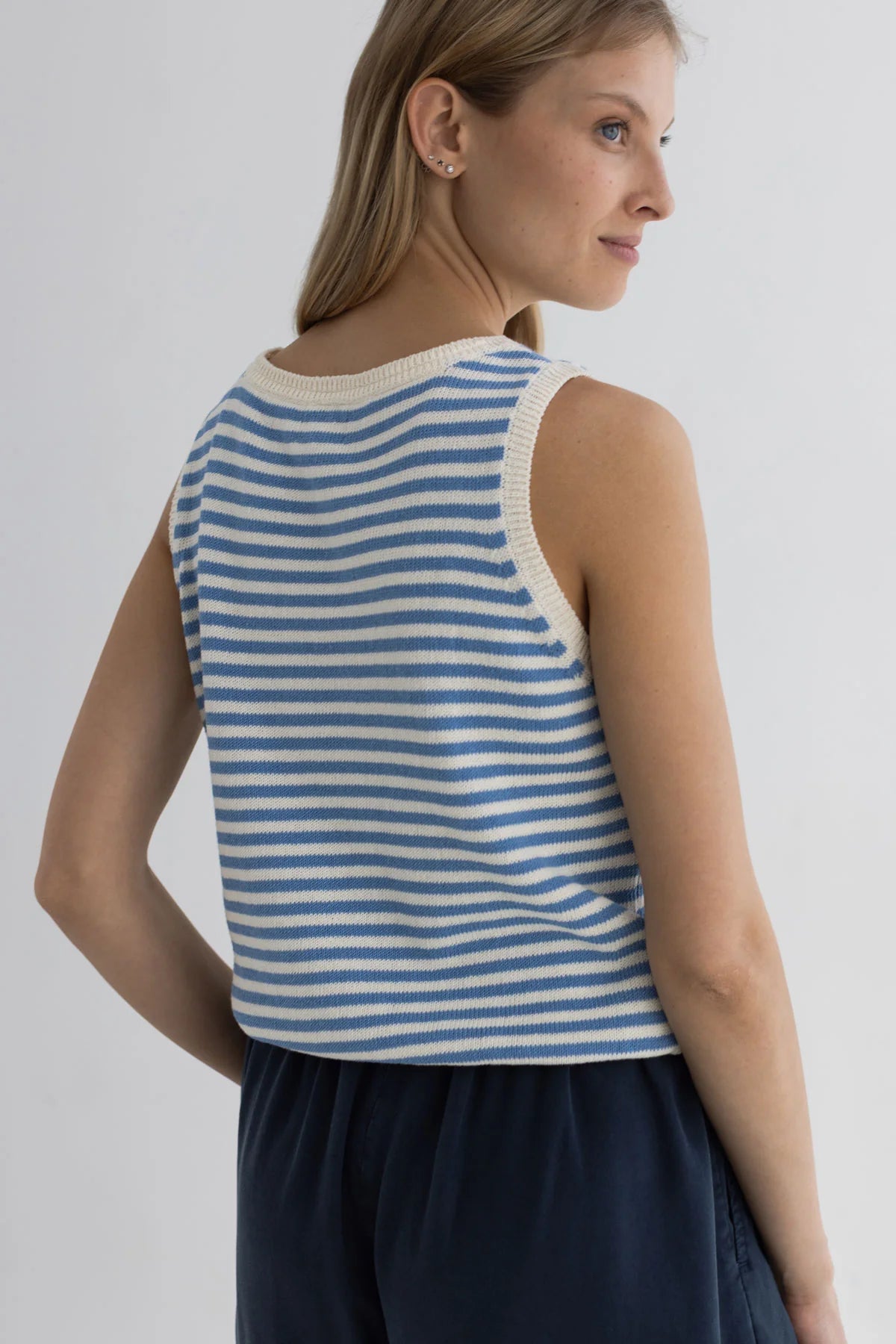 Woman wearing a blue and white striped sleeveless top against a plain background