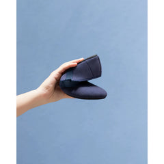 Hand holding a navy blue shoe against a light blue background