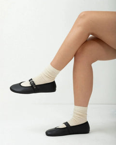 Person wearing black shoes and white socks on a white background