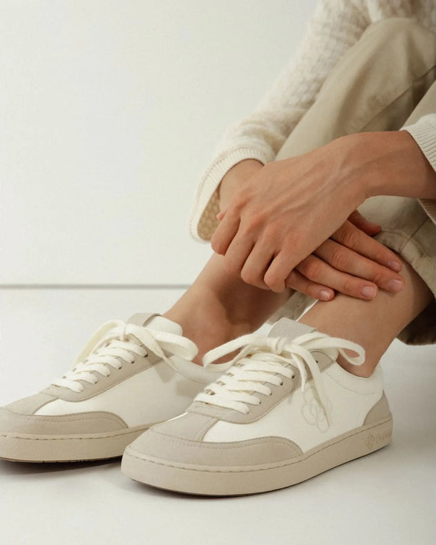 White sneakers worn with beige pants on a light background