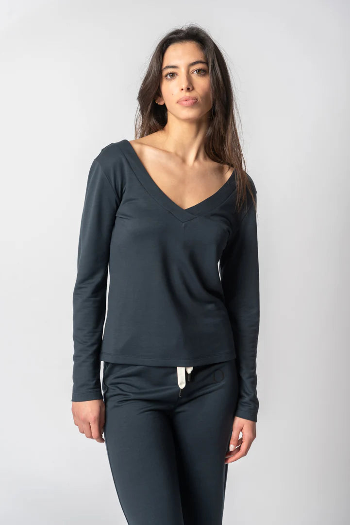 A woman modeling a dark charcoal gray long-sleeve V-neck top and matching dark gray leggings against a light gray studio background.