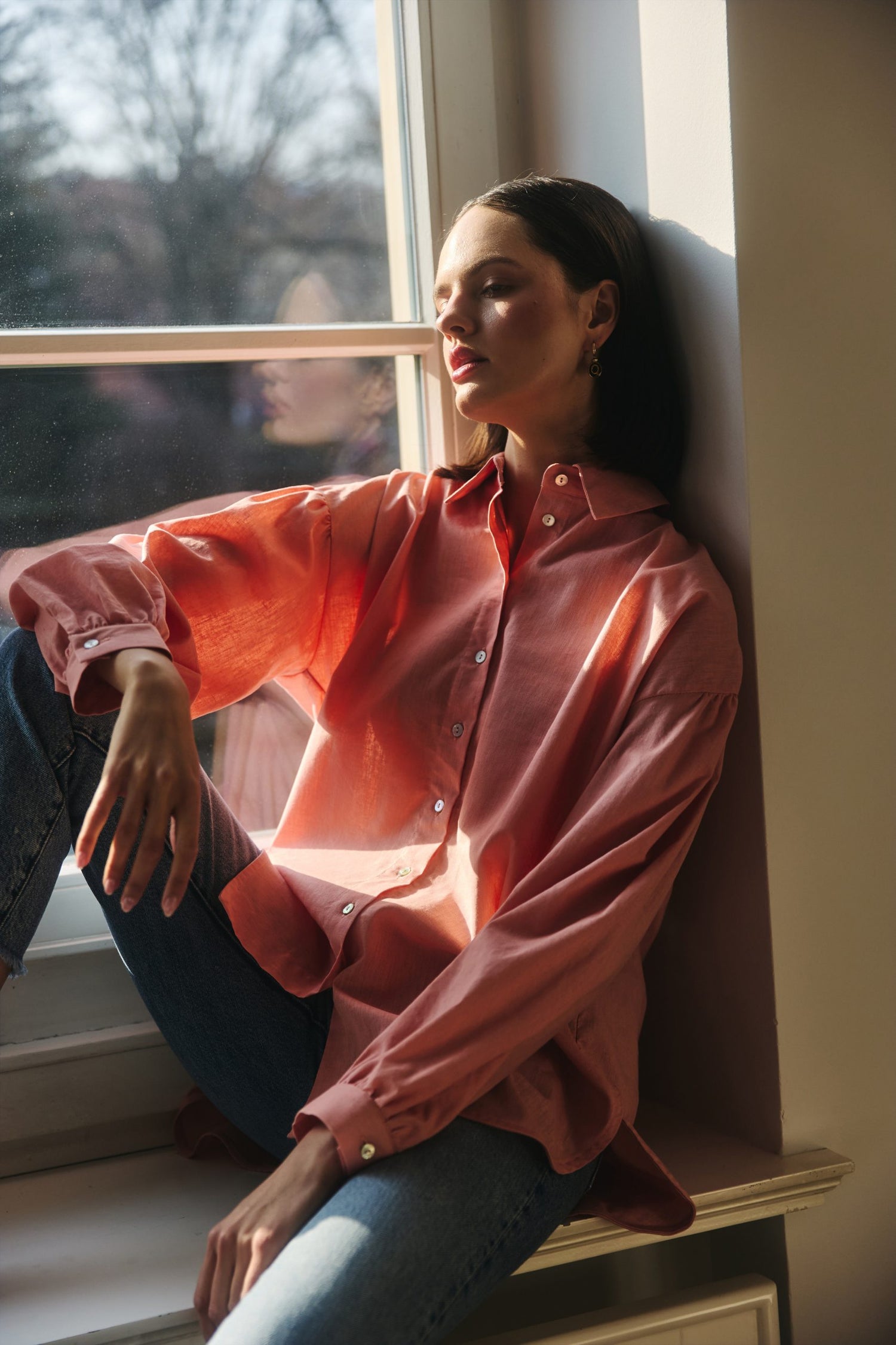 Woman wearing a pink shirt sitting by a window