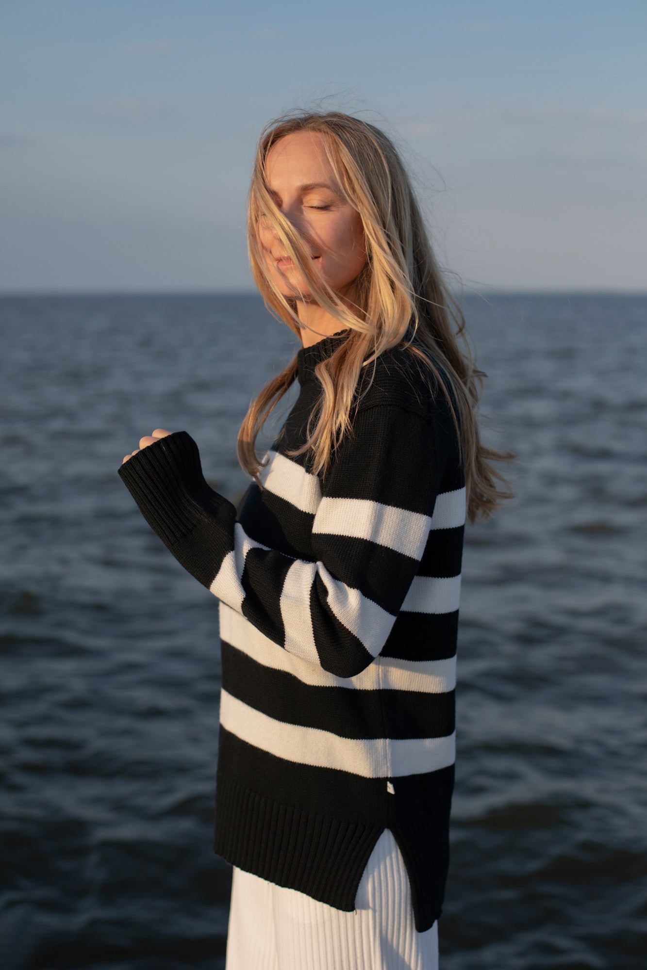 Woman wearing a black and white striped sweater by the ocean
